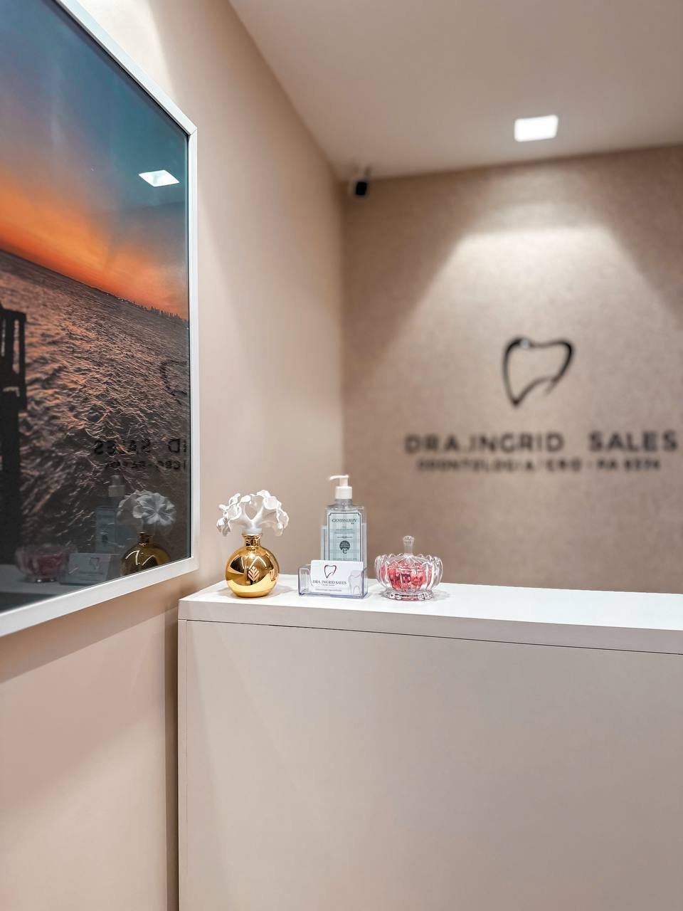 Recepção do consultório da Dra. Ingrid Sales — ambiente acolhedor com tons bege e detalhes dourados